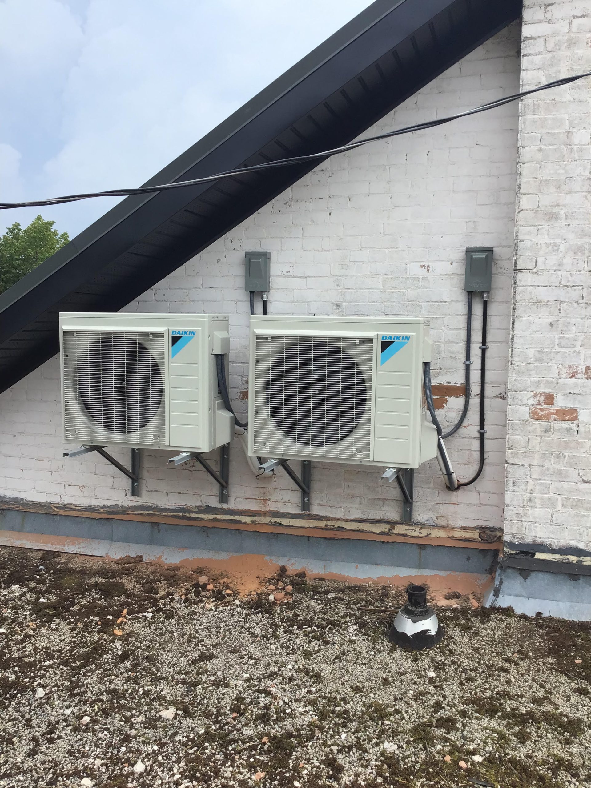 Ductless heat pump wall units installed on brick exterior by Crose Mechanical